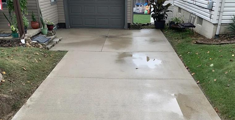 A concrete driveway cleaned by Bronny's Power Washing, back to an even light finish.